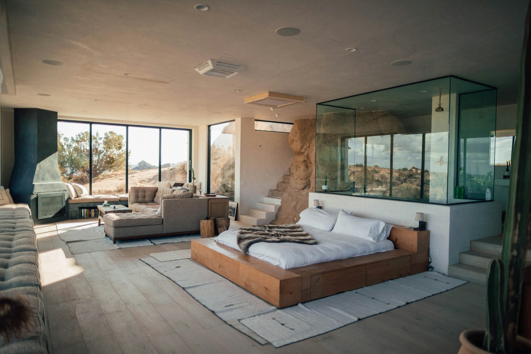 The Vale Suite — a low bed under dark timber beams, lit by a single brass lamp