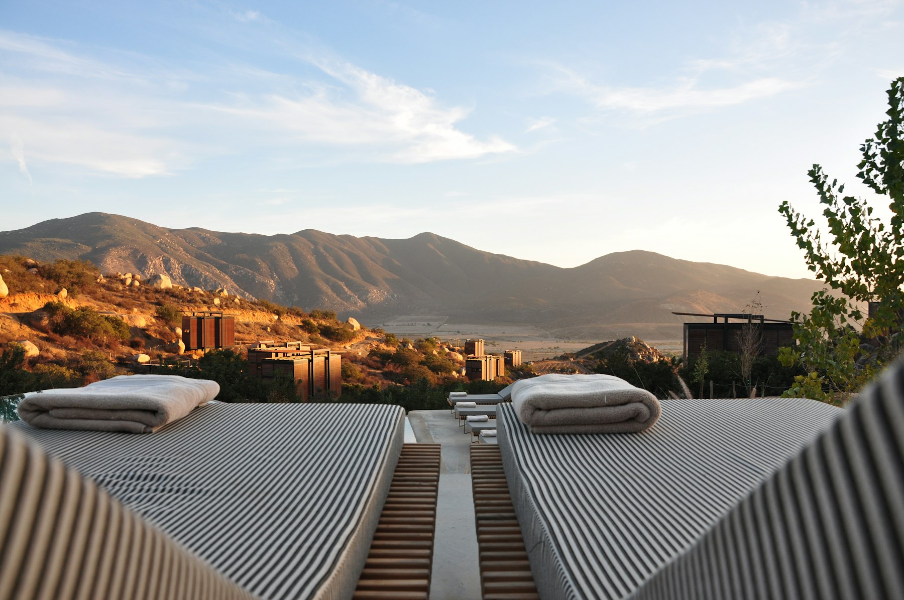The Pool House terrace at golden hour, daybeds facing the hills