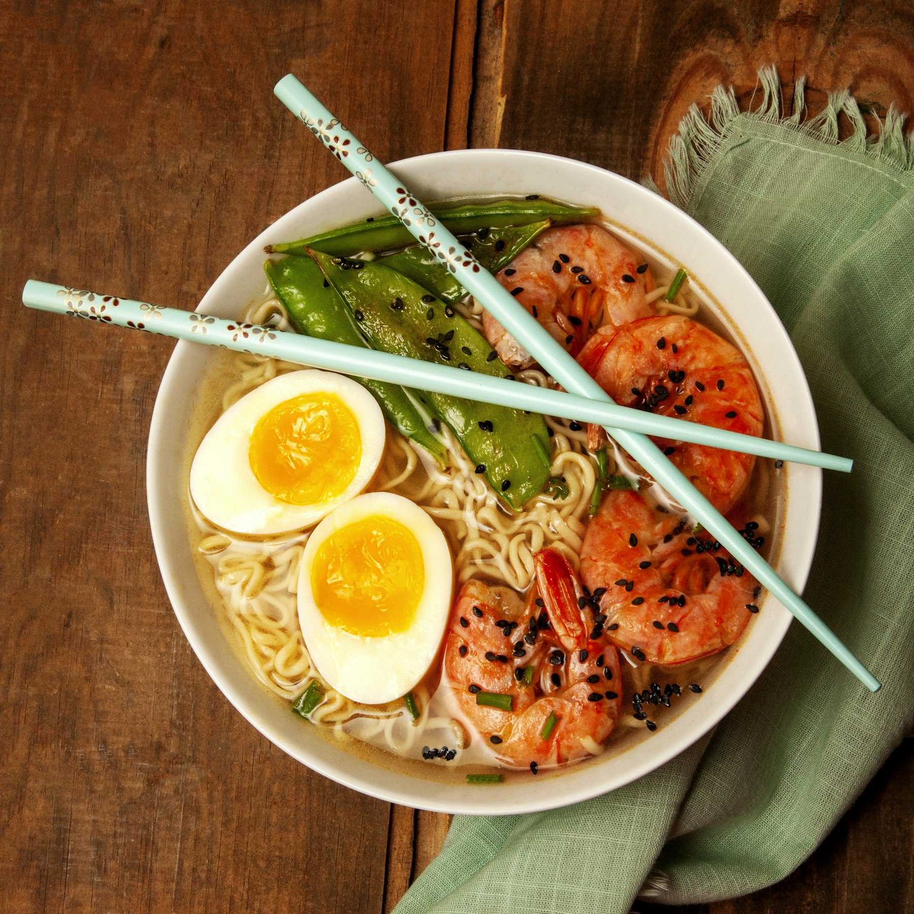 A bowl of ramen with soft egg and chopsticks