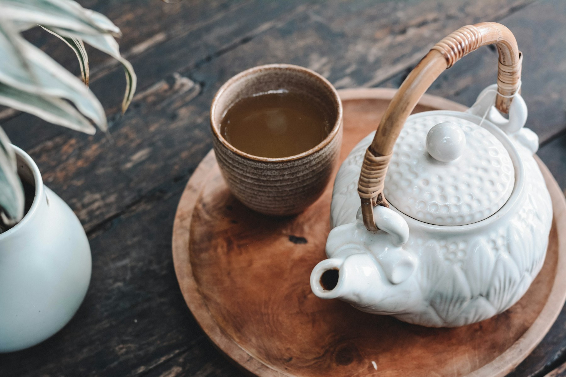 A ceramic teapot and cup on a wooden tray