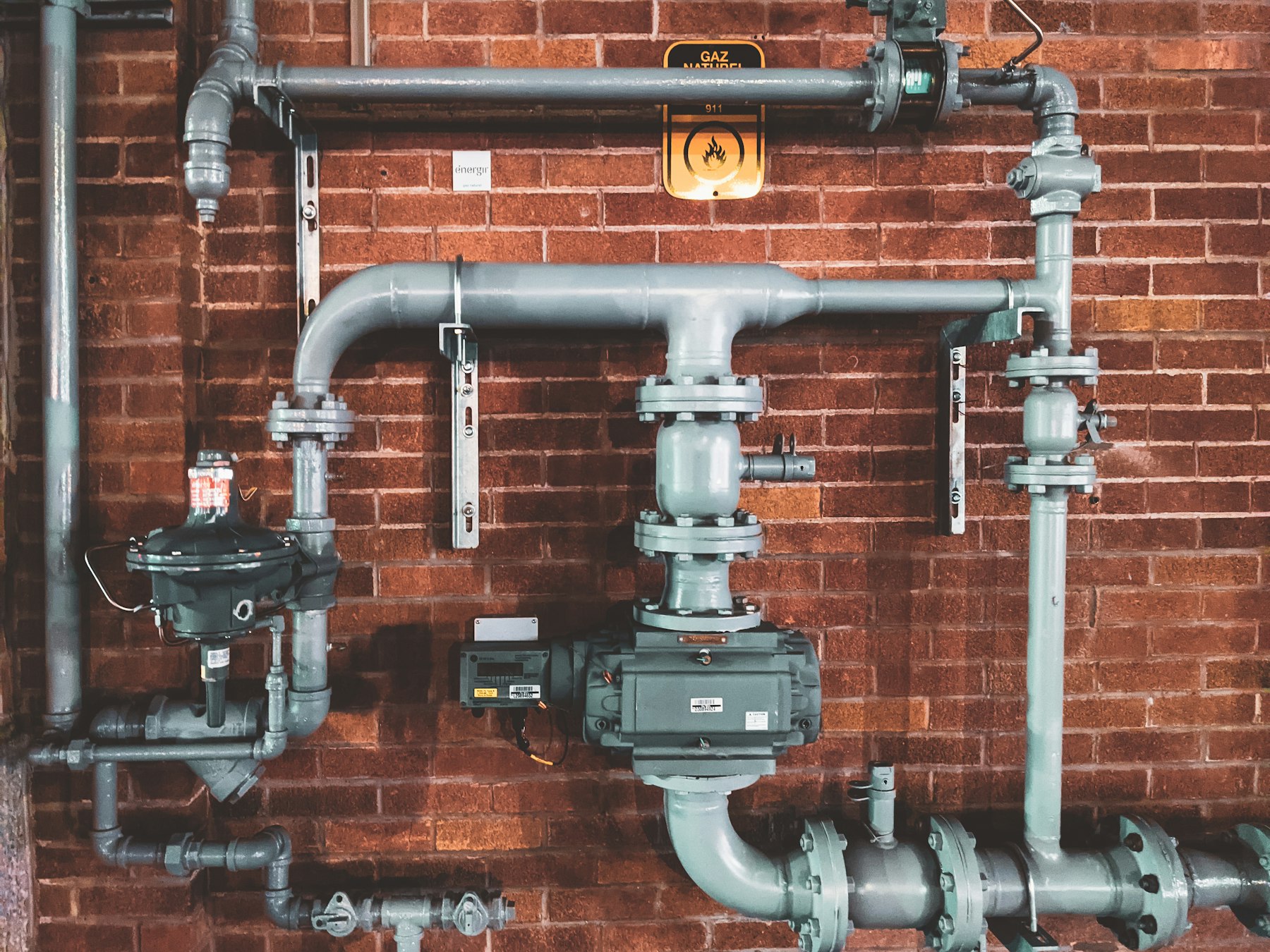 Industrial pipework against a brick wall